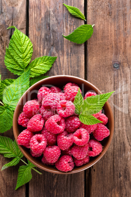 Fresh raspberry with leaves on wooden background