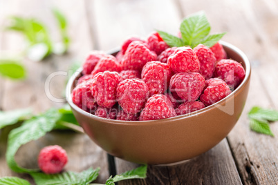 Fresh raspberry with leaves on wooden background