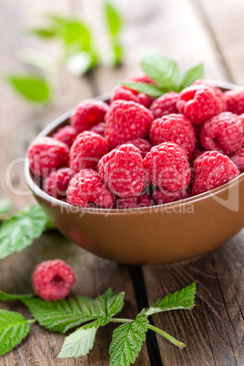 Fresh raspberry with leaves on wooden background