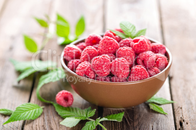 Fresh raspberry with leaves on wooden background