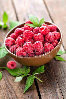 Fresh raspberry with leaves on wooden background