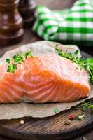 Raw salmon fish fillet on wooden board closeup