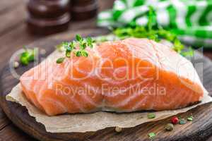 Raw salmon fish fillet on wooden board closeup