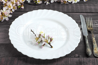 Empty white ceramic plate with vintage iron cutlery on a brown w
