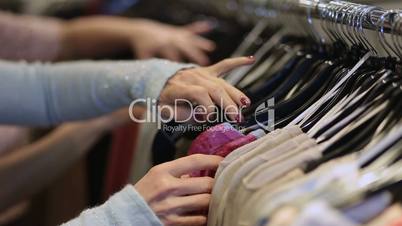 Female hands selecting colorful clothes on hangers