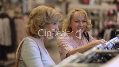 Senior women choosing dress while shopping in shop