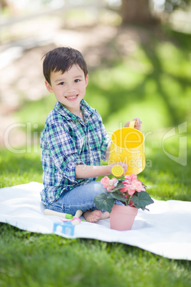 Mixed Race Young Boy Watering His Potted Flowers Outside On The