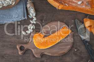 Piece of fresh orange pumpkin on a kitchen cutting board