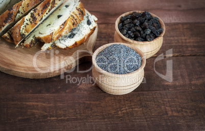 Poppy seeds and raisins in wooden bowls on a brown surface