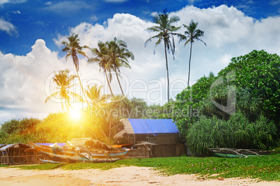 old fishing boats and huts on sandy beach and sunset