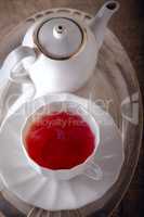 A cup of Red fruit tea with a kettle.