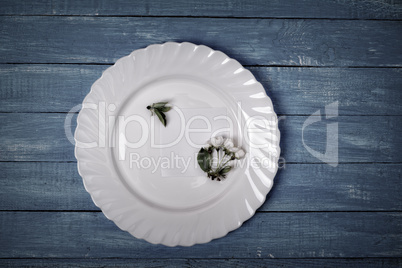 White dish with paper leaf on a blue wooden surface
