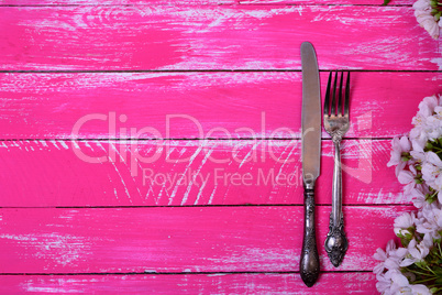 Vintage fork and knife on a pink wooden surface