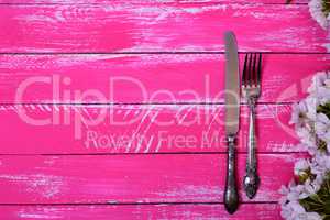 Vintage fork and knife on a pink wooden surface