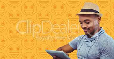 Man in fedora with tablet against yellow emoji pattern