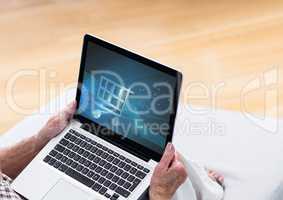 Person using laptop with Shopping trolley icon