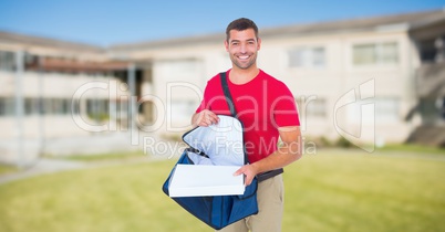Delivery man removing pizza box from bag against house