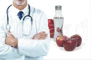 Midsection of male doctor with fruits and drink in background