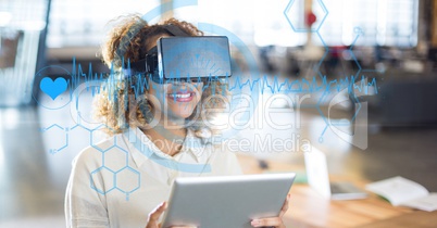 Digital composite image of heart pulses and various icons with woman using VR glasses and tablet com