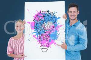 Portrait of couple holding billboard with colorful light bulb icon against blue background