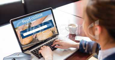 Cropped image of woman searching food online on laptop at table in coffee shop