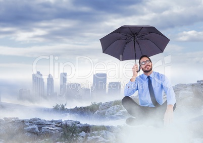 Business man legs crossed with umbrella on misty mountain peak against skyline