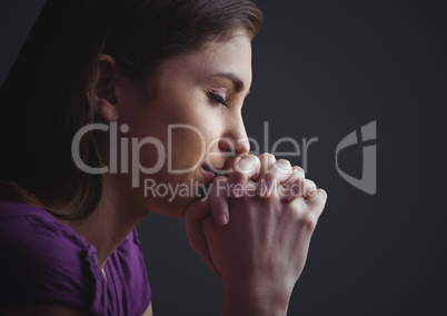 Woman praying against dark grey background