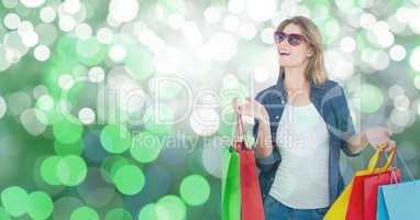 Surprised woman with carrying shopping bags over bokeh