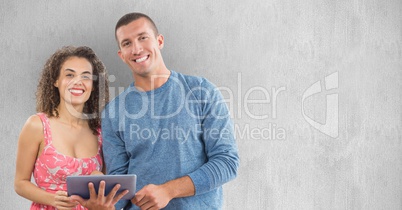 Smiling man and woman using tablet PC against wall