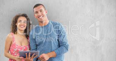 Smiling man and woman using tablet PC against wall