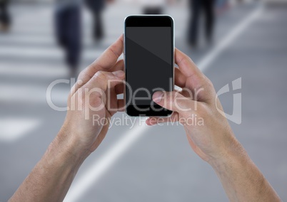 Hands with phone against blurry street with people