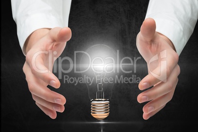 Digitally generated image of hand covering electric bulb against gray background