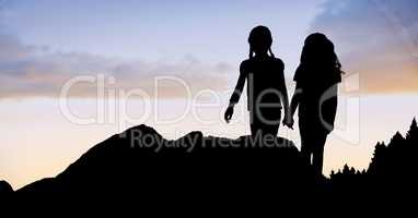 Silhouette girls holding hands on mountain against sky