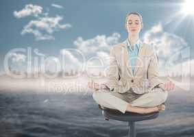 Business woman meditating on chair against water and blurry skyline with flare