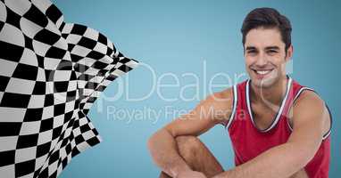 Male runner sitting on track against blue background with checkered flag