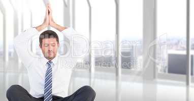 Business man meditating with hands over head against blurry white window