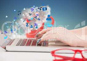 Hands on laptop with icons and clouds coming from screen against blue green background