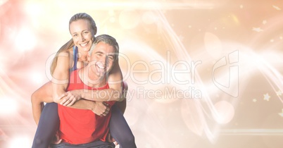Happy fit man giving piggyback ride to woman over bokeh