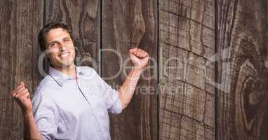 Happy businessman celebrating success against wooden wall