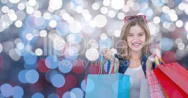 Portrait of woman smiling while holding colorful bags over bokeh