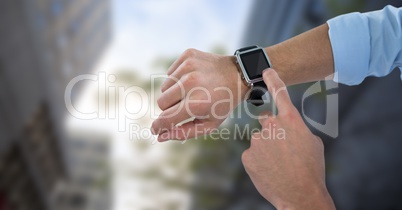 Hands with watch against blurry buildings and sky