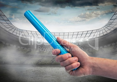 Hand with blue baton against stadium with flare