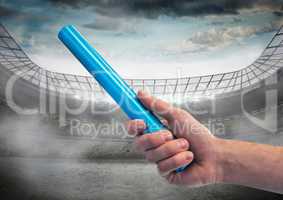 Hand with blue baton against stadium with flare