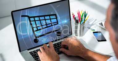 Cropped image of businessman using laptop with shopping cart on screen