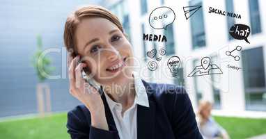 Digital composite image of businesswoman using phone by various icons against building