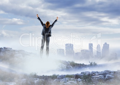 Business woman cheering on misty mountain peak against skyline