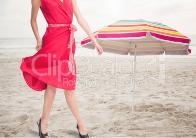 Womans legs standing on beach by umbrella