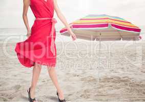 Womans legs standing on beach by umbrella