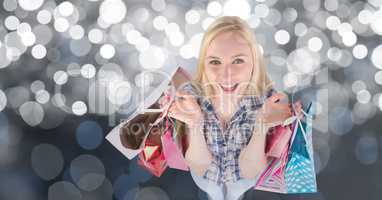 Happy woman with shopping bags over bokeh