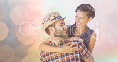 Happy man giving piggyback ride to woman over bokeh